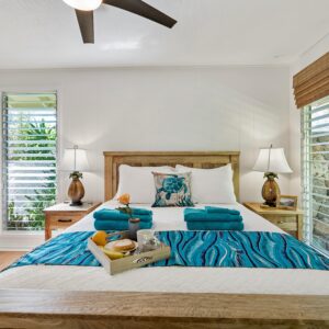 Bright bedroom interior with blue accents, natural light, and tropical decor.